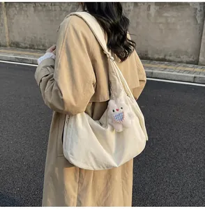 Detail of a beige canvas crescent hobo bag with a cute white plush bunny charm