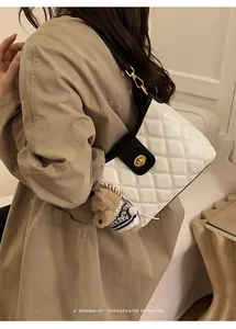 Classic white quilted bag with black strap and dog charm shown on a khaki trench coat