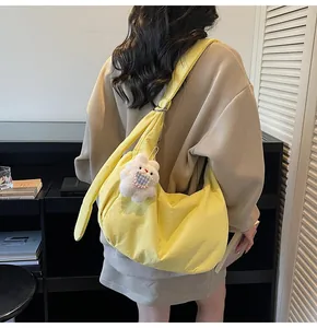 Detail of a bright yellow cotton-padded hobo bag with cute white rabbit plush charm