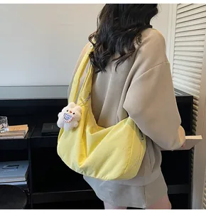 Detail of yellow crescent shoulder bag with plush rabbit charm worn by a model