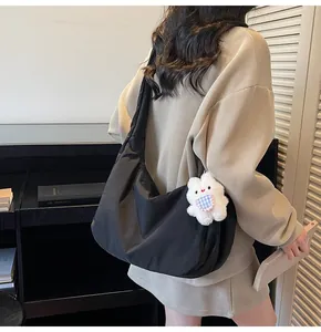 Close-up of a black padded half-moon tote bag featuring a cute plush bear charm detail