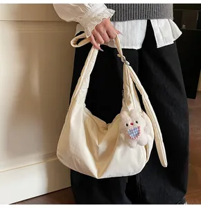 Detail of off-white padded tote bag with soft pleats and cute plush bunny charm
