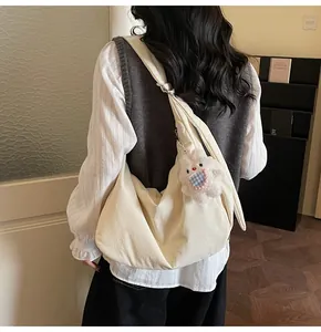 Detail of cream canvas crossbody bag with soft texture and cute white rabbit pendant