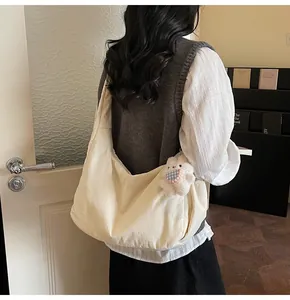 Detailed back view of a large beige crossbody tote bag with cute plush pendant accessory