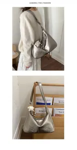 Detail of silver metallic hobo bag with pleated texture and stylish doll pendant