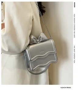 Detail of silver handbag with bow decoration and stylish wavy edges on metallic surface
