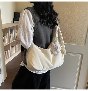 Detail of a large beige quilted tote bag with a white plush bunny charm on a wide shoulder strap