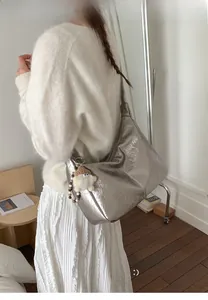 Silver metallic pleated tote bag with cute plush pendant on a model's shoulder