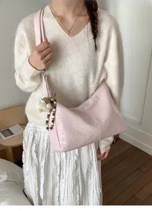 Detail of light pink tote bag featuring a plush bear charm and beaded decorative chain
