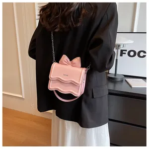 Pink wavy bottom crossbody bag with bow detail and KCMK lettering close-up