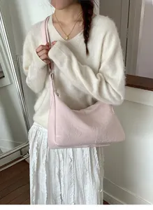 Detail of light pink tote bag with pleated texture shown on shoulder for daily commute