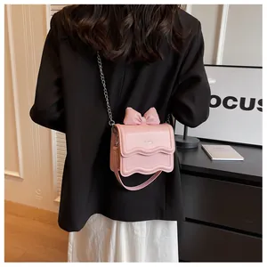 Detail of pink fashion bag featuring a 3D leather bow and metallic chain strap