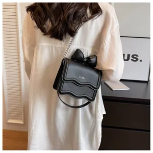 Close-up of black crossbody bag featuring a large bow and silver chain strap details