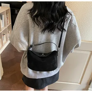 Rear view of model wearing a black matte suede hobo bag with silver twist lock
