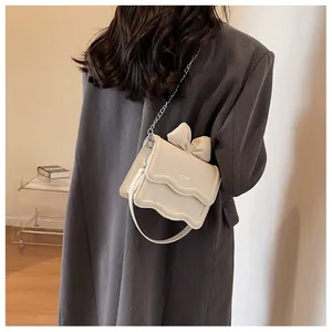 Detail of cream PU leather square bag with bow tie accent and wavy edge design