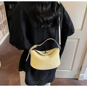 Detail of creamy yellow baguette bag with silver twist lock and adjustable shoulder strap