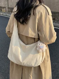 Off-white crescent shoulder bag with plush bunny pendant shown on a trench coat