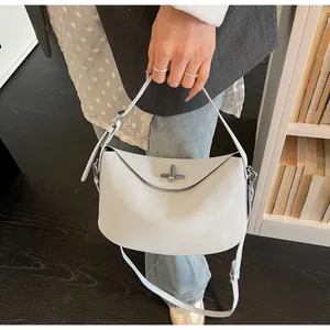 Detail of elegant cream faux leather baguette bag with silver metal turn-lock clasp
