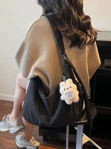 Black nylon crescent shoulder bag with plush rabbit charm for daily commuting style