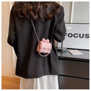 Detailweergave van de roze handtas met strik en zilveren ketting gedragen door een model