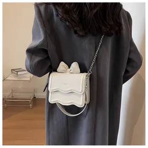Detail of cream white leather bag with wavy edge, bow decor and KCMK lettering