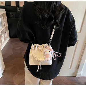 Detail of cream drawstring bucket bag with star quilting and cute plush doll pendant