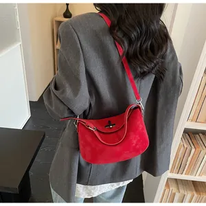 Detail of red matte suede crossbody bag with silver buckle worn on gray suit