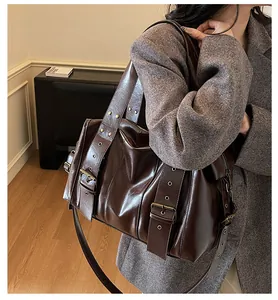 Dettaglio borsa shopper in pelle marrone scuro con fibbie vintage e occhielli metallici