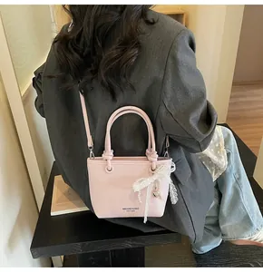 Dettaglio della borsa a secchiello rosa chiaro con fiocco in pizzo e ciondolo a cuore