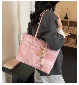 Bolso tote rosa de tela con textura y colgante de oso sobre un conjunto de blazer