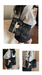 Detalle del bolso tote de cuadros grises con correa de cuero sintético negro y oso