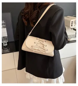 Detail of cream bow crossbody bag with corset lace-up design and silver eyelets