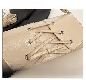 Detail of cream pleated leather crossbody bag with decorative rope and silver eyelets