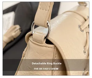 Detail of detachable silver metal buckle and soft leather texture on beige baguette bag