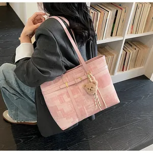 Detalle del bolso tote de cuadros rosas con colgante de oso y herrajes dorados