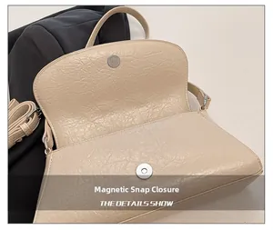 Detail of cream baguette bag featuring magnetic closure and premium oil wax leather texture
