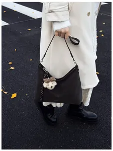 Detail der braunen Vintage-Wildleder-Tragetasche mit Teddybär-Anhänger im Straßenbild