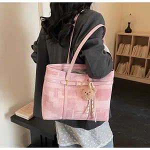 Detalle de bolso rosa con textura de píxel, hebilla fina y colgante de oso de peluche