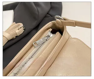 Detail of smooth silver metal zipper on stylish beige crossbody bag with lychee texture