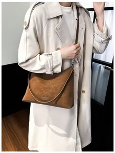 Detailaufnahme der braunen Wildledertasche mit Lederlogo und feinem Schultergurt