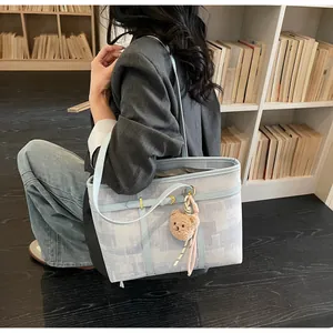 Detalle de bolso tote con estampado azul claro y colgante de oso en una librería