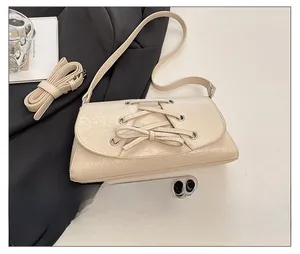Detail of cream crossbody bag with bow decoration and phone for size reference