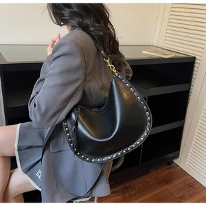 Detail of black crescent bag with golden metal studs and polished hardware finish