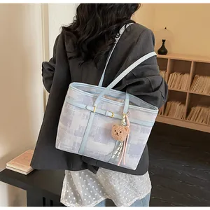 Primer plano del bolso tote azul claro con colgante de oso y detalles en cuero fino