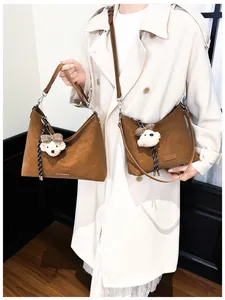 Detail der braunen Wildledertasche mit verstellbarem Ledergurt und Plüschbär-Anhänger