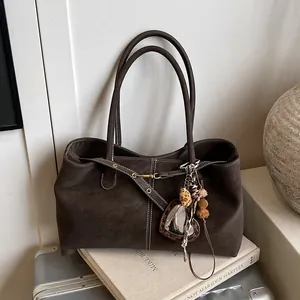 Détail du sac cabas marron foncé avec surpiqûres contrastées et breloques décoratives