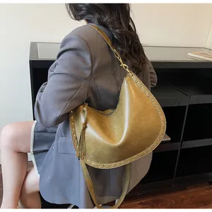 Detail of olive green crescent tote with golden rivets and matte leather texture