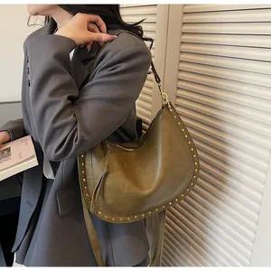 Detail view of olive green hobo bag featuring matte leather and golden rivet accents