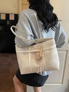 Bolso tote grande crema con estampados geométricos y colgante de oso usado por modelo