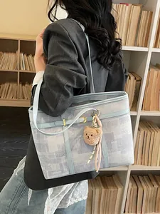 Bolso tote grande con textura abstracta azul y colgante de oso llevado por una modelo